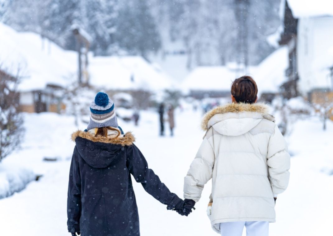 Een stelletje loopt hand in hand door het dorp Ouchi-juku in de winter