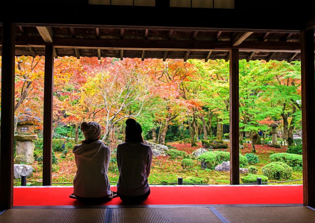 Twee jonge vrouwen zitten in de tuin van de Enkoji-tempel in Kyoto, Japan