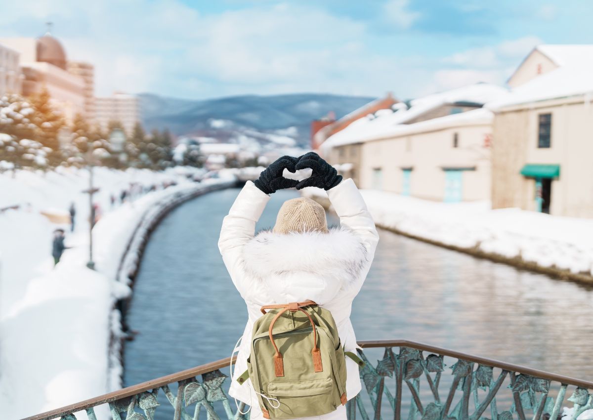 Blije reizigster met rugzak in het besneeuwde Otaru
