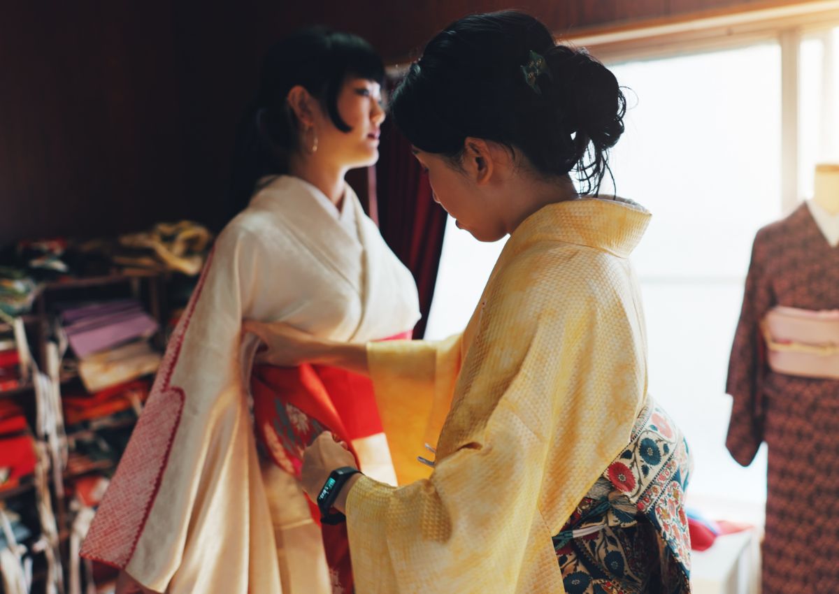 Vrouw helpt een andere vrouw met het aantrekken van een kimono