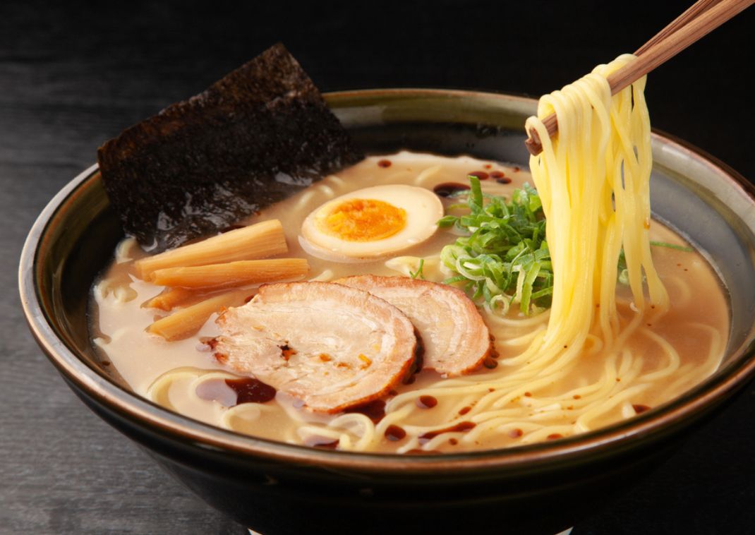 Een bord ramen: rijke bouillon met smaakvolle noedels, geserveerd met toppings zoals zachtgekookt ei, varkensvlees en groenten