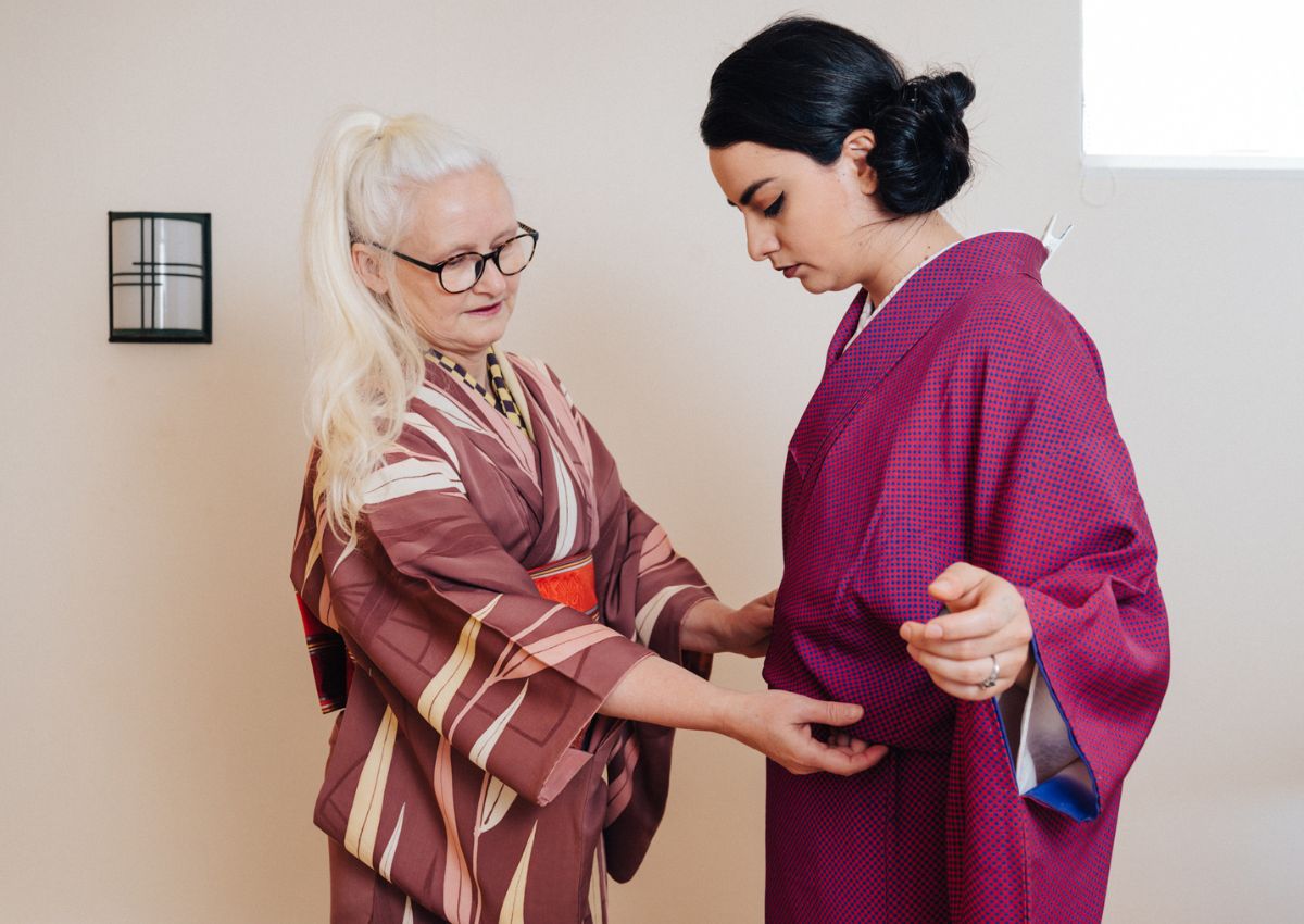 Kimono-instructeur helpt een vrouw aankleden in kimono
