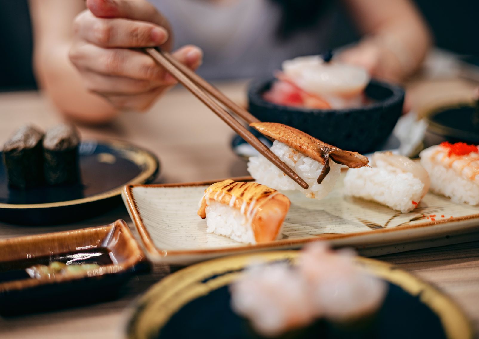 Japanse vrouw pakt een nigiri-sushi met eetstokjes
