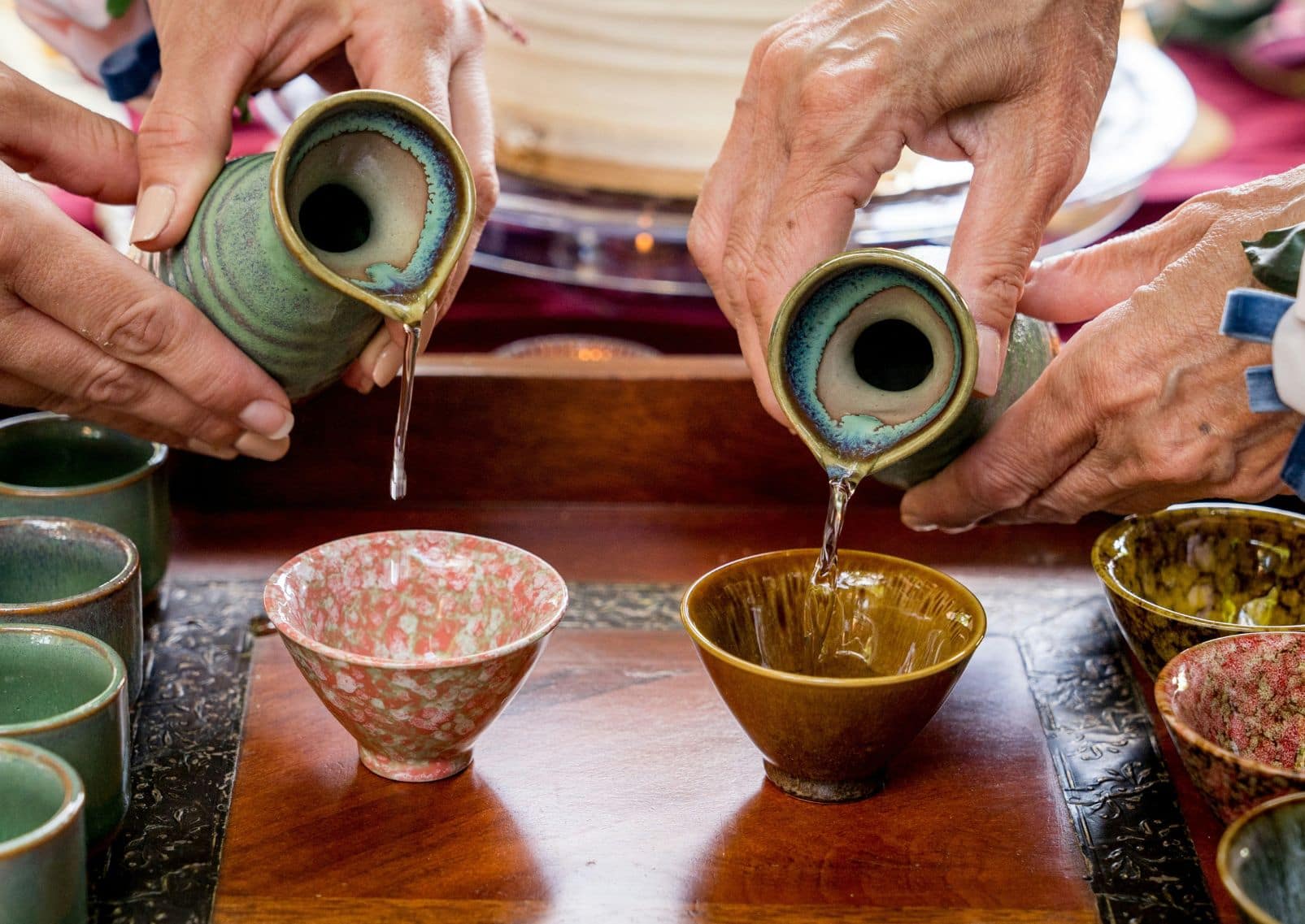 Mensen schenken Japanse sake in traditionele kopjes