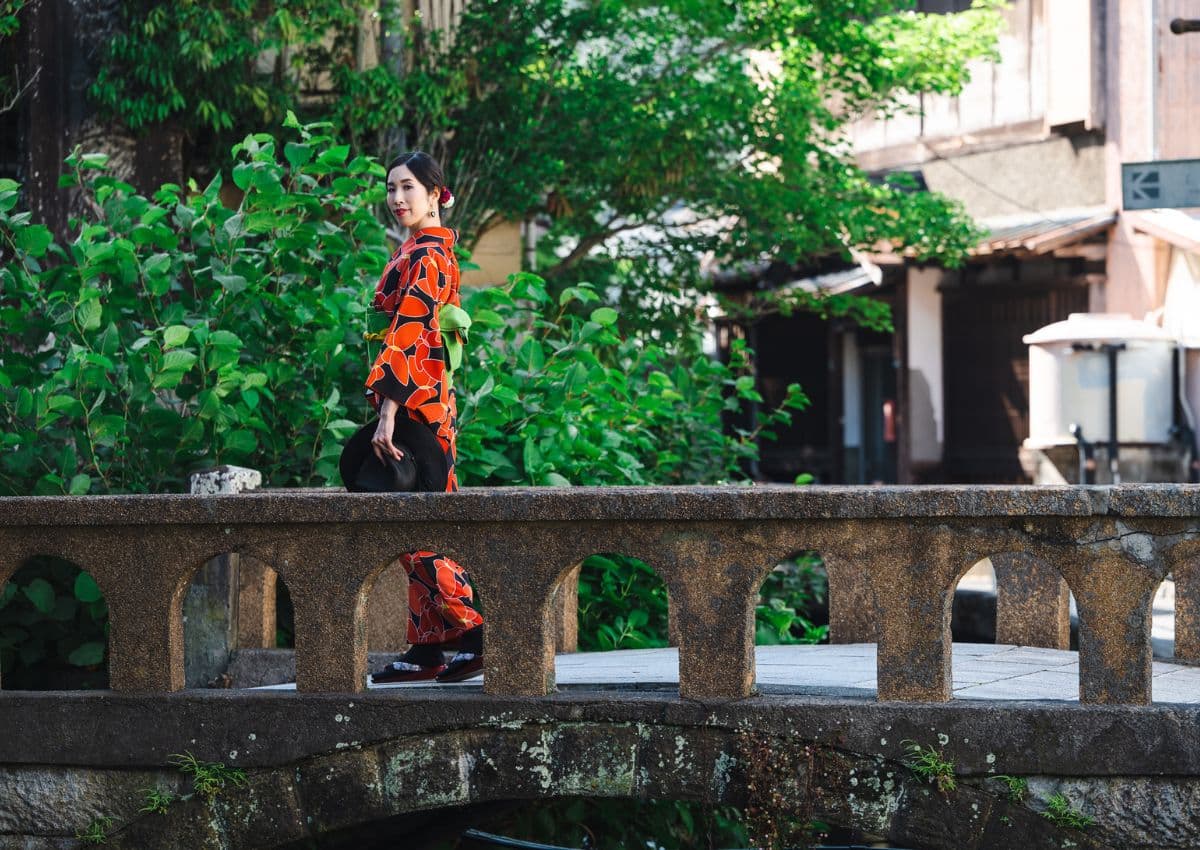 Vrouw in kimono die over een brug wandelt in het landelijke Japan