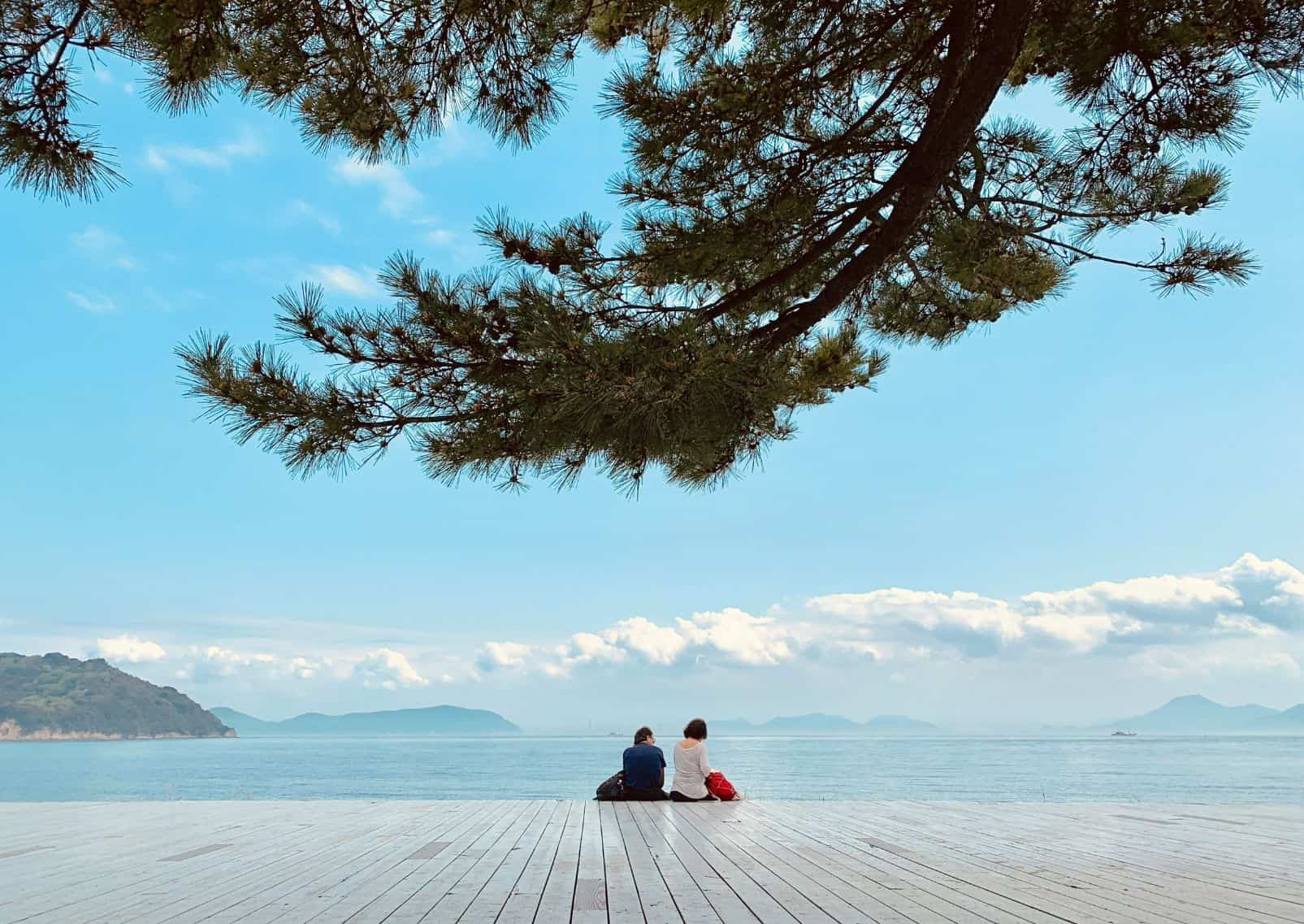  Mensen zitten aan de zonnige kust van Naoshima.