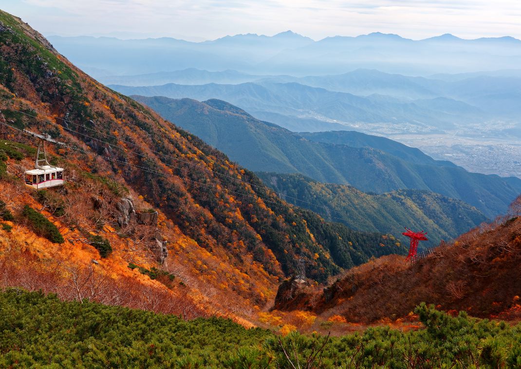Een kabelbaan zweeft boven de herfstkleuren in de Kiso-bergketen op weg naar Senjojiki Cirque, Japan