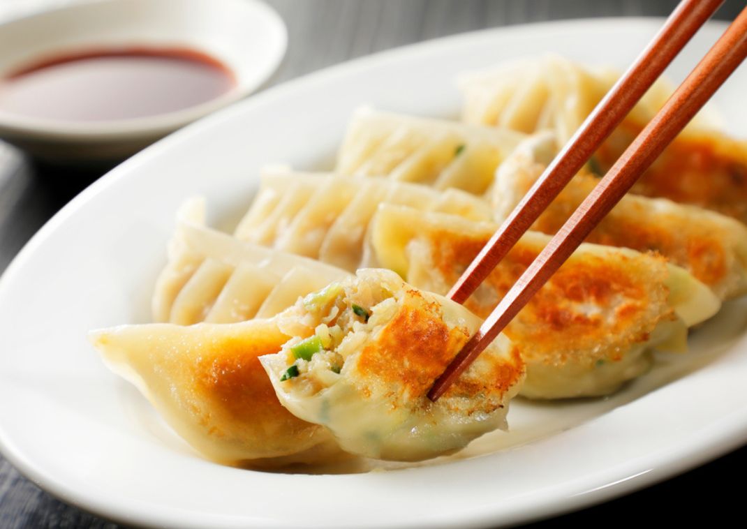 Heerlijke gebakken gyoza die omhoog worden gehouden met eetstokjes.