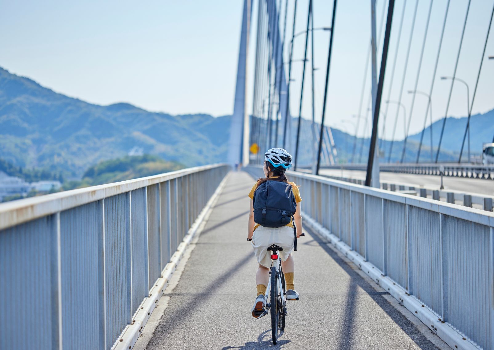 Vrouw fietst op de Shimanami Kaido fietsroute, Japan.