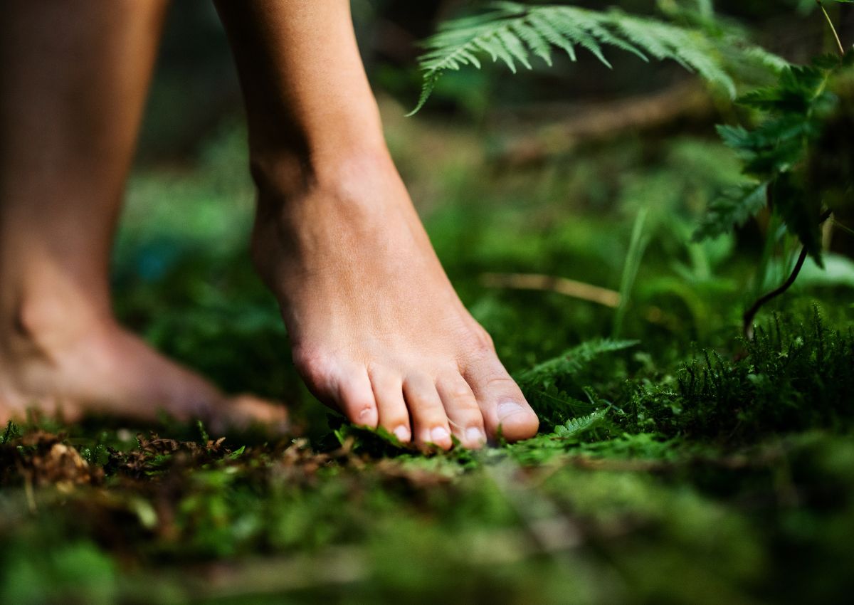 Jonge vrouw die blootsvoets door het bos loopt