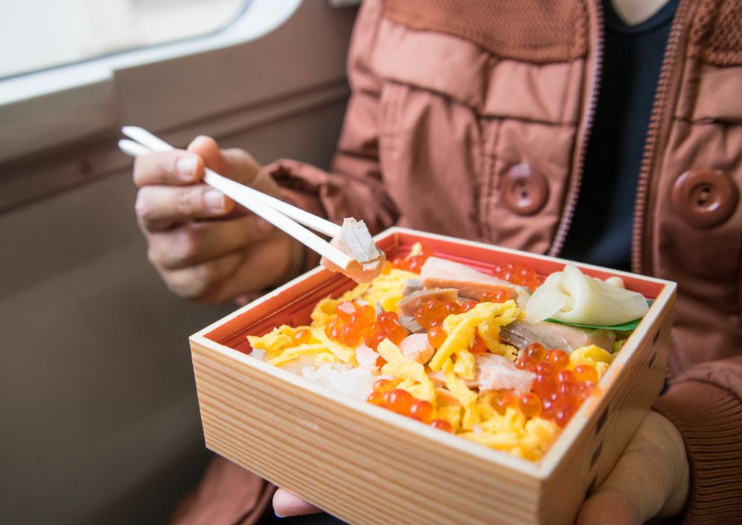 Toerist die Japans bento-eten eet uit een houten bak in de trein