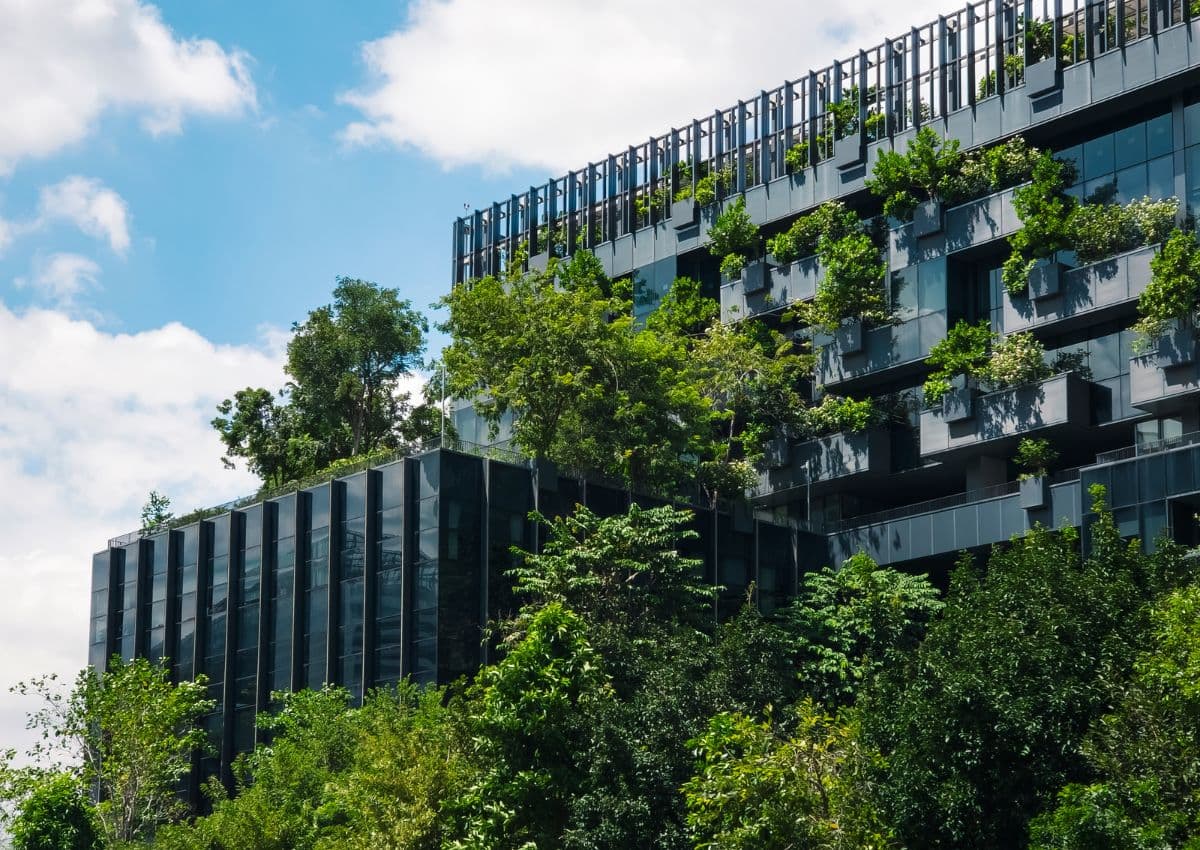Duurzaam ecologisch gebouw: milieuvriendelijk glazen gevelontwerp met bomen; concept van ecologie, gezondheid en welzijn