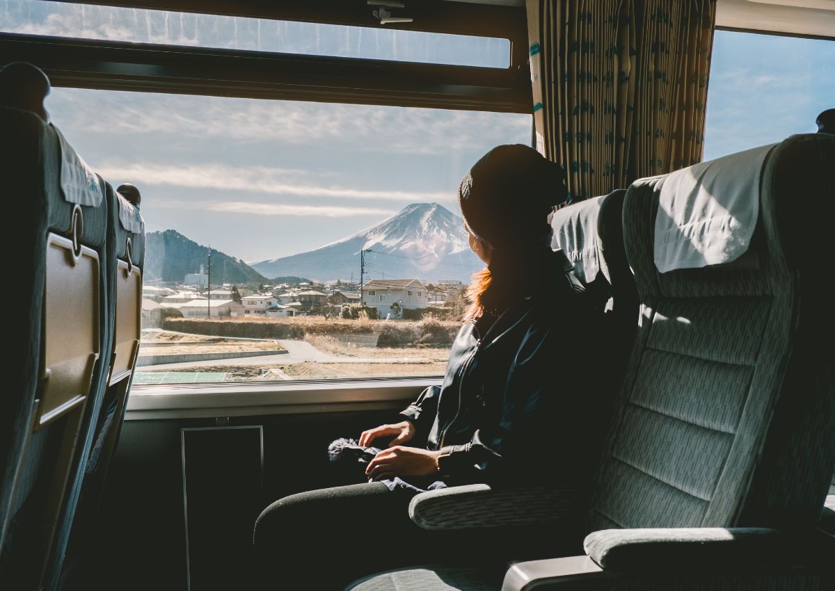 A Woman travelling on the train near the window, with a view of Mount Fuji.