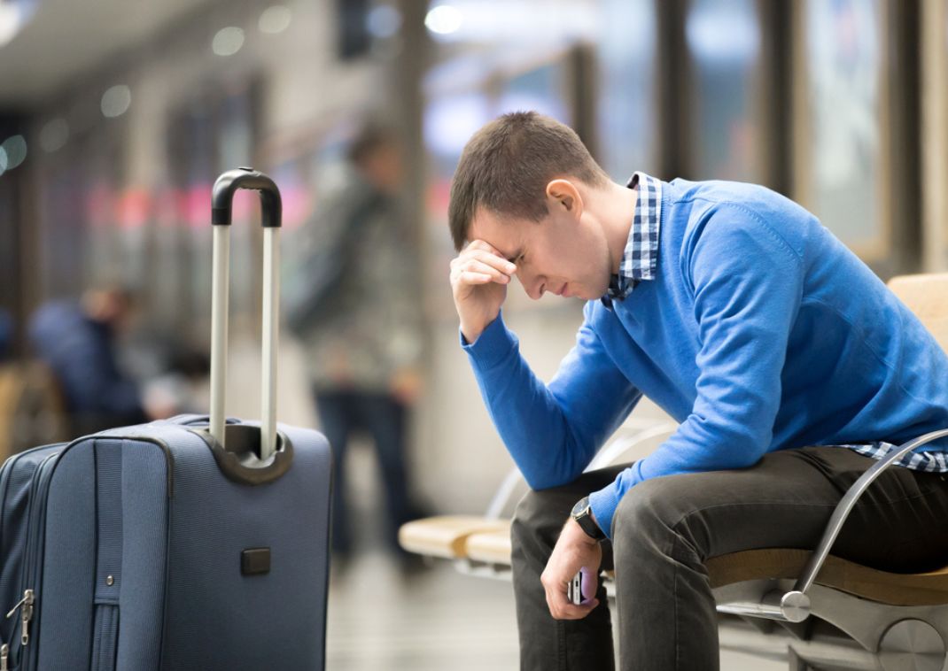 Man in het vliegveld met bagage, teleurgesteld omdat hij zijn vlucht heeft gemist.