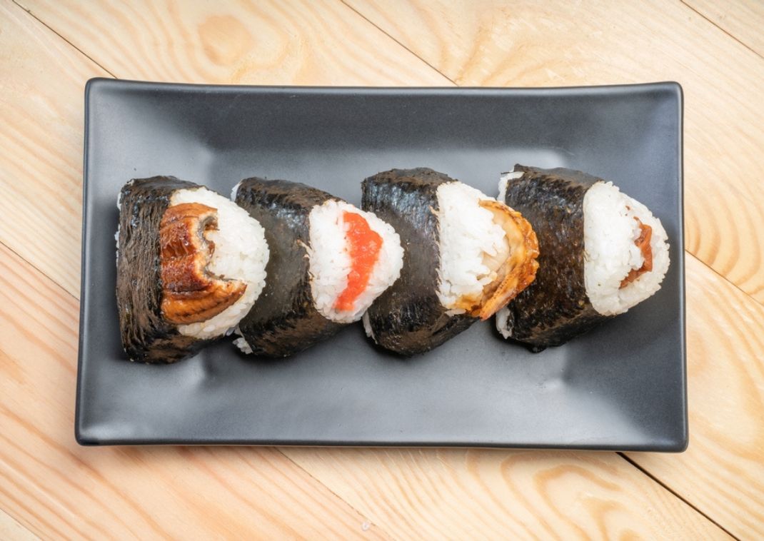 Een bord met onigiri's: hartige rijstbal gevuld met vis of ingelegde pruim, gewikkeld in zeewier.