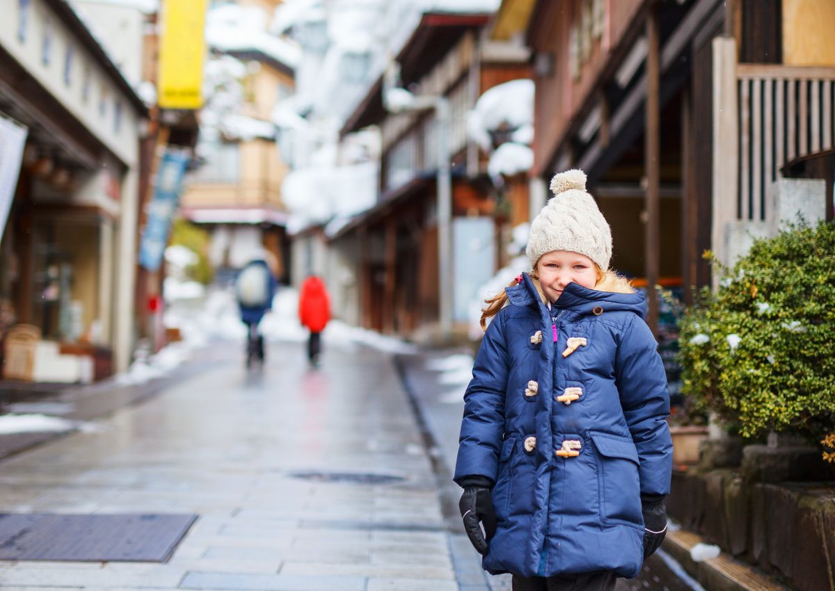 Klein meisje in de straten van een besneeuwd Japans onsenstadje