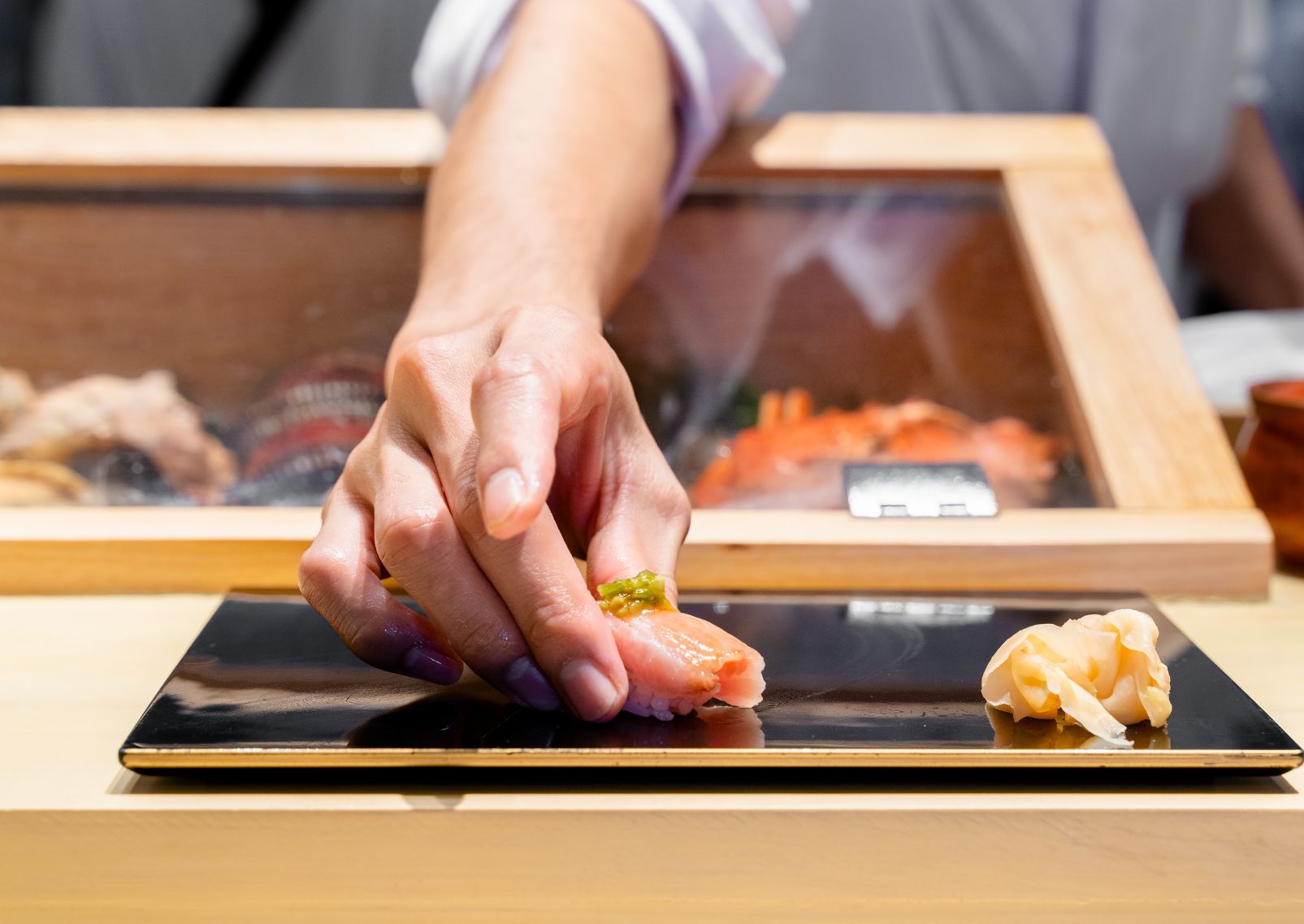 Japanse sushichef serveert een vers bereide nigiri-sushi tijdens een omakase-ervaring