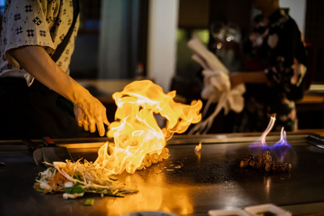 Chef-kok bereidt teppanyaki-maaltijd met gegrild rundvlees en groenten