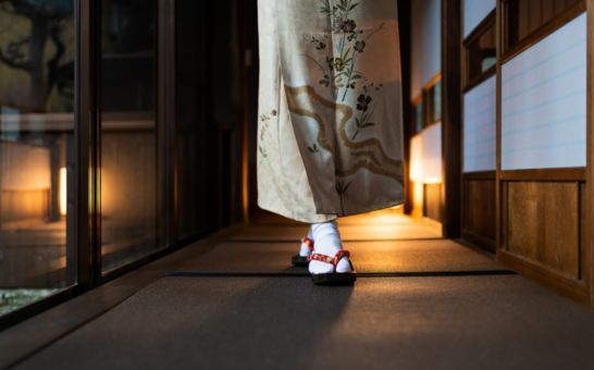 Vrouw in kimono loopt door een traditionele ryokan met tatami matten en shoji deuren