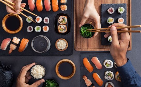 Assortiment sushi waaronder nigiri, sashimi en rollen die worden gedeeld en gegeten met stokjes