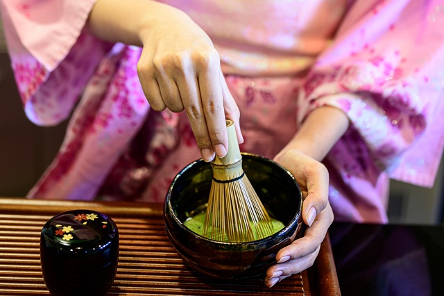 Dame in kimono die Japanse groene thee maakt