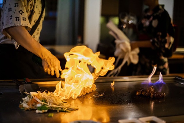 Chef-kok bereidt teppanyaki-maaltijd met gegrild rundvlees en groenten