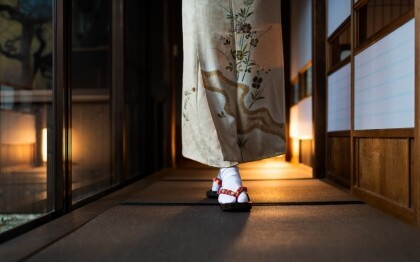 Vrouw in kimono loopt door een traditionele ryokan met tatami matten en shoji deuren