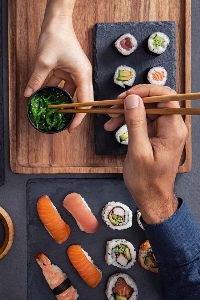 Assortiment sushi waaronder nigiri, sashimi en rollen die worden gedeeld en gegeten met stokjes